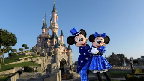 Disney characters Mickey and Mini mouse pose in front of the Sleeping Beauty Castle to mark the 25th anniversary of Disneyland - originally Euro Disney Resort - on March 16, 2017 in Marne-La-Vallee, east of the French capital Paris