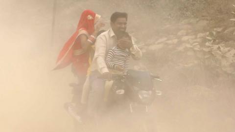 Indian family on motorbike in heavily polluted air