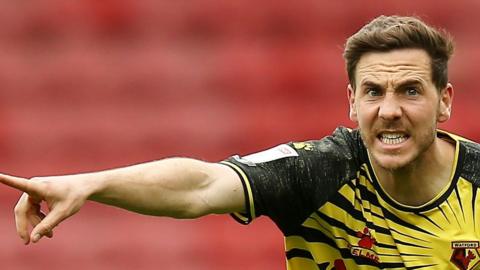 Dan Gosling points with an angry expression on his face while in action for Watford