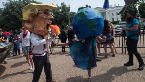 Protesters wearing a mask of US President Donald Trump and one of the Earth pretend to fight in front of the White House during the People's Climate March in Washington, DC, on April 29, 2017