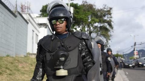 Police officers belonging to the COBRA Special Riot Command stand guard next to supporters of opposition candidate Salvador Nasralla as they hold a protest march on December 6, 2017 in Tegucigalpa.