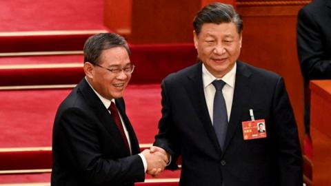 China's President Xi Jinping (R) shakes hands with newly-elected Premier Li Qiang