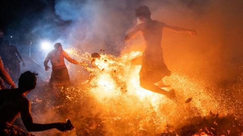 Balinese man kicks burnt coconut husks during the fire fight ritual called Mesabatan Api on March 21, 2023 in Gianyar, Bali, Indonesia.