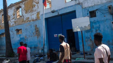 People walk in front of the Haitian National Penitentiary, after the attack last night by armed gangs in Port-au-Prince, Haiti, on 3 March 2024