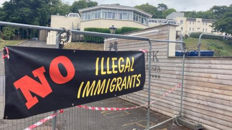 Sign on a fence in front of the hotel saying no illegal immigrants