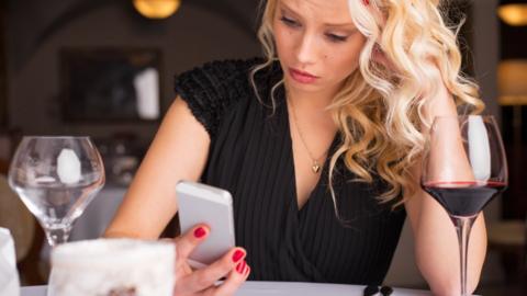 Worried woman looking at phone in restuarant