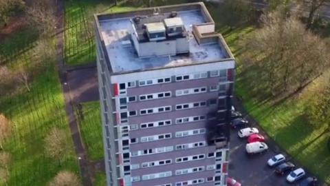 Footage captured by a drone camera shows the damage caused to a tower-block in Dunmurry, County Antrim