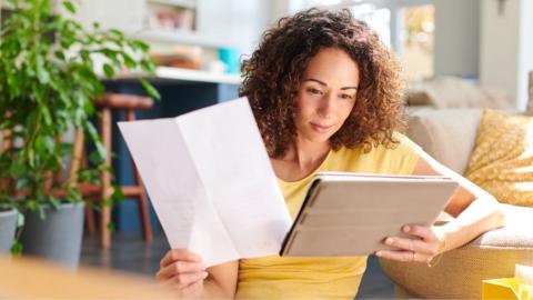 Stock image of a woman looking at a letter and a laptop