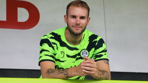 Teddy Jenks poses in a Forest Green Rovers shirt after signing for the League Two club