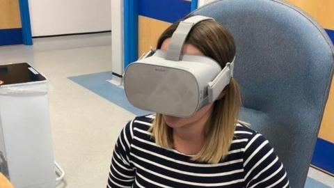 Pregnant woman sitting in a hospital chair wearing a VR headset