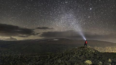 A person looking at the stars in the Clwydian Range and Dee Valley Area of Outstanding Natural Beauty