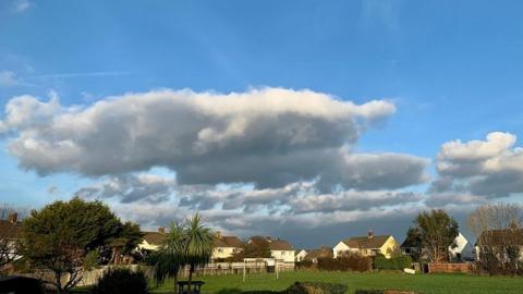 Blue skies with flat cumulus clouds over houses