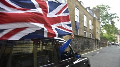 Cab driver waves Union Flag from his vehicles on the day after Brexit referendum