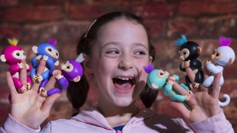 A girl plays with the Fingerlings toy