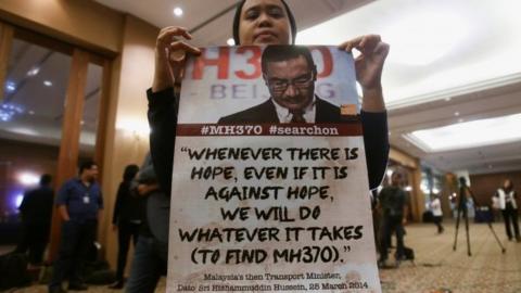 A family member of a passenger onboard the missing Malaysia Airlines flight MH370, shows a poster before the start of a news conference following a meeting with Joint Agency Coordination Centre (JACC) in Kuala Lumpur, Malaysia July 21, 2016.