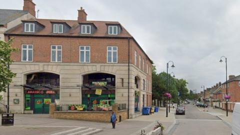 Three-storey brick and stone building in corner of Market Place with dinosaur-themed window dressing