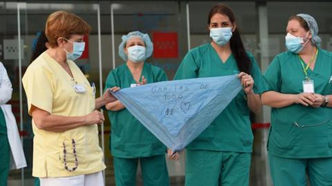 Spanish hospital workers hold a bandana reading 'thanks for all the love'
