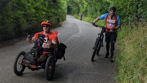 Tom Green and a friend cycling up a hill