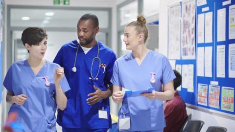 3 nhs nurses walking down corridor