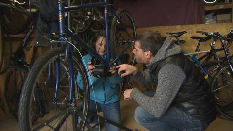 Beth Ward and Robin Hughes work to convert an old bike to an e-bike