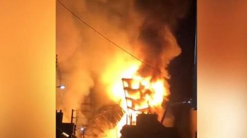 A huge fire tears through two disused buildings in the French city of Rouen, causing them to collapse.