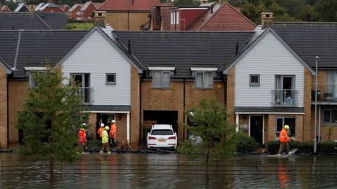 Water utilities workers talk with residents from flooded houses, in Hemel Hempstead, Herts on 4 October 2020