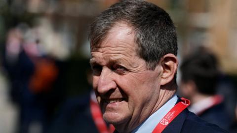 Alastair Campbell pictures from the side with the sun in his face
