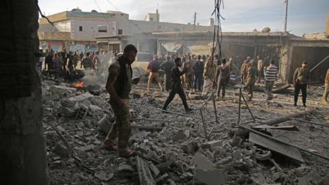 Turkey-backed Syrian fighters inspect the site of a car bomb explosion in the northern Syrian Kurdish town of Tal Abyad, on the border with Turkey, on November 2, 2019.