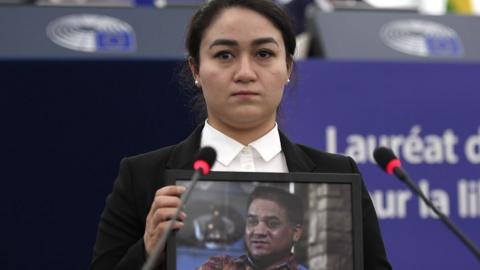 Jewher Ilham holding a portrait of her father, Ilham Tothi, during the award ceremony on December 18