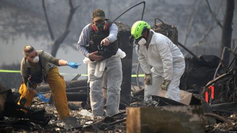 Rescue workers search an area burned by the Camp Fire, in Paradise, California (16 Nov)