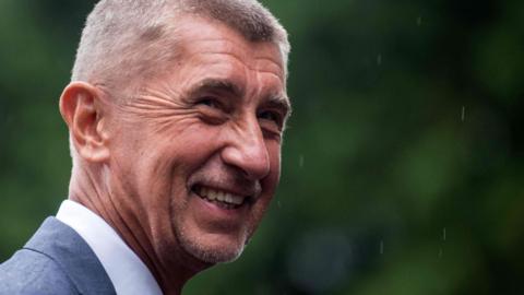 Andrej Babis smiles in the rain in this photo from late August