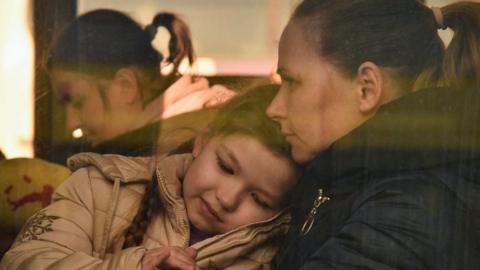 A child pets a cat in a bus for refugees fleeing Russia"s invasion of Ukraine, in Lviv on 13 March