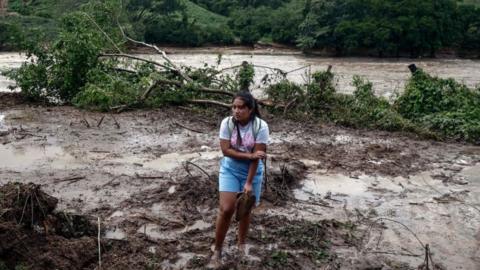 A woman stand amid mud and debris at the Kilometro 42 community, near Acapulco, Guerrero State, Mexico, after the passage of Hurricane Otis, on October 25, 2023.