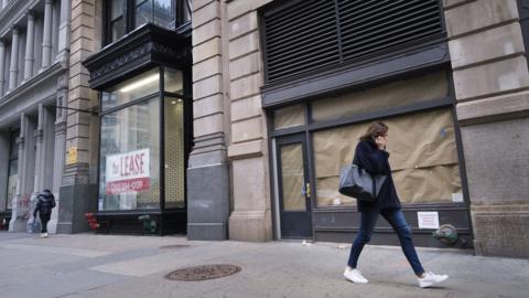 a woman walks by a closed store