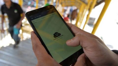 An Indian Kashmiri man browses blocked services on the internet on his mobile phone on a footbridge in Srinagar on April 27, 2017. -