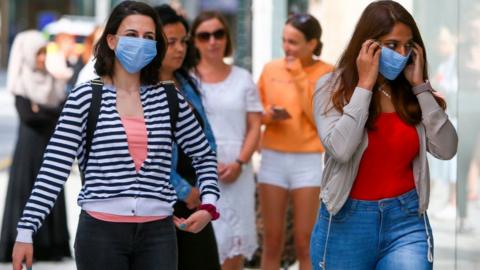 Two women wearing masks in the street