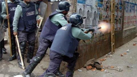 File photo of a Bangladeshi policeman firing tear gas at opposition activists