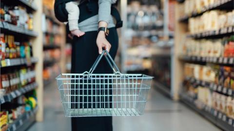Cropped shot of mother carrying a shopping cart, doing grocery shopping in supermarket - stock photo