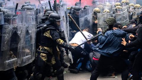 Soldiers with batons and shields clash with protesters