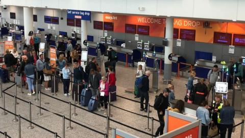 People queuing at Bristol Airport check in desks