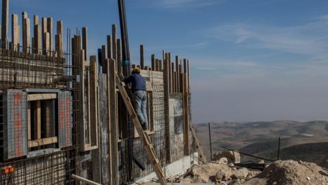 A Palestinian worker builds a new house in an Israeli Settlement on January 16, 2017 in the West Bank.