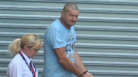 Gene Charles Bristow in handcuffs is escorted by a guard to Adelaide's District Court