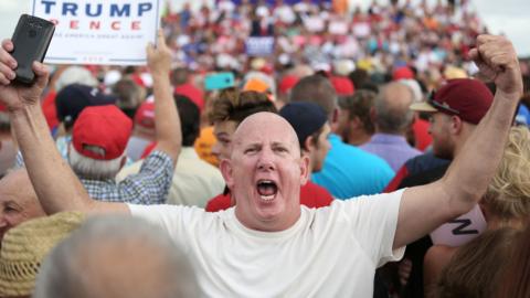 A supporter of Republican presidential nominee Donald Trump gestures at the media during a campaign stop inside a hangar at Lakeland Linder Regional Airport in Lakeland, Florida on October 12, 2016