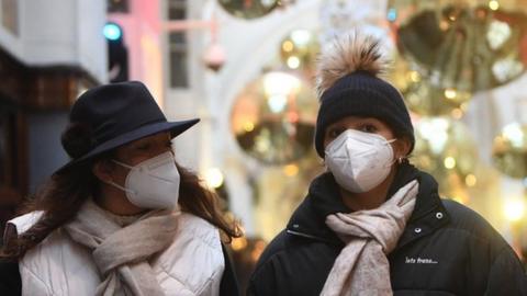 Shoppers pass Christmas decorations on a store in London