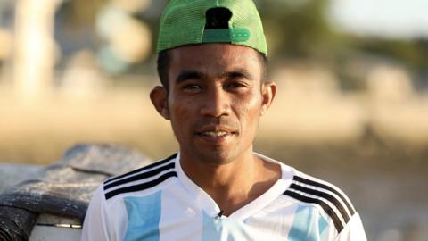 Abdul on the beach, wearing a cap backwards