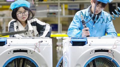 Employees work on a washing machine at a factory in Qingdao, in eastern China's Shandong province on 18 February, 2024.