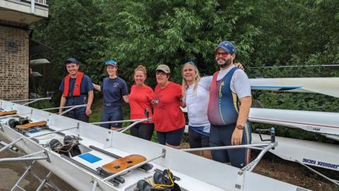 Members of the Adaptive Rowing club gathered around a boat