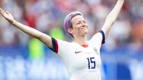 Megan Rapinoe with her arms in the air celebrating
