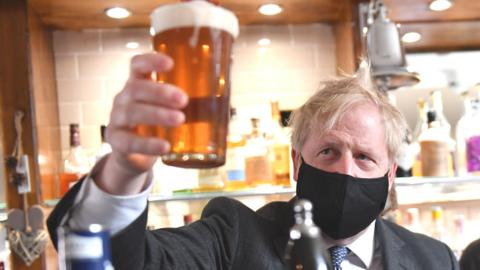 Boris Johnson holding a pint of beer in a pub