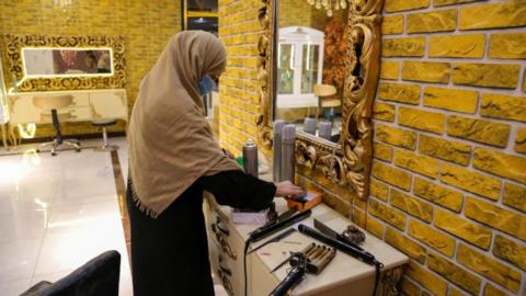A woman prepares to leave after closing a beauty salon in Kabul, 4 July 2023.